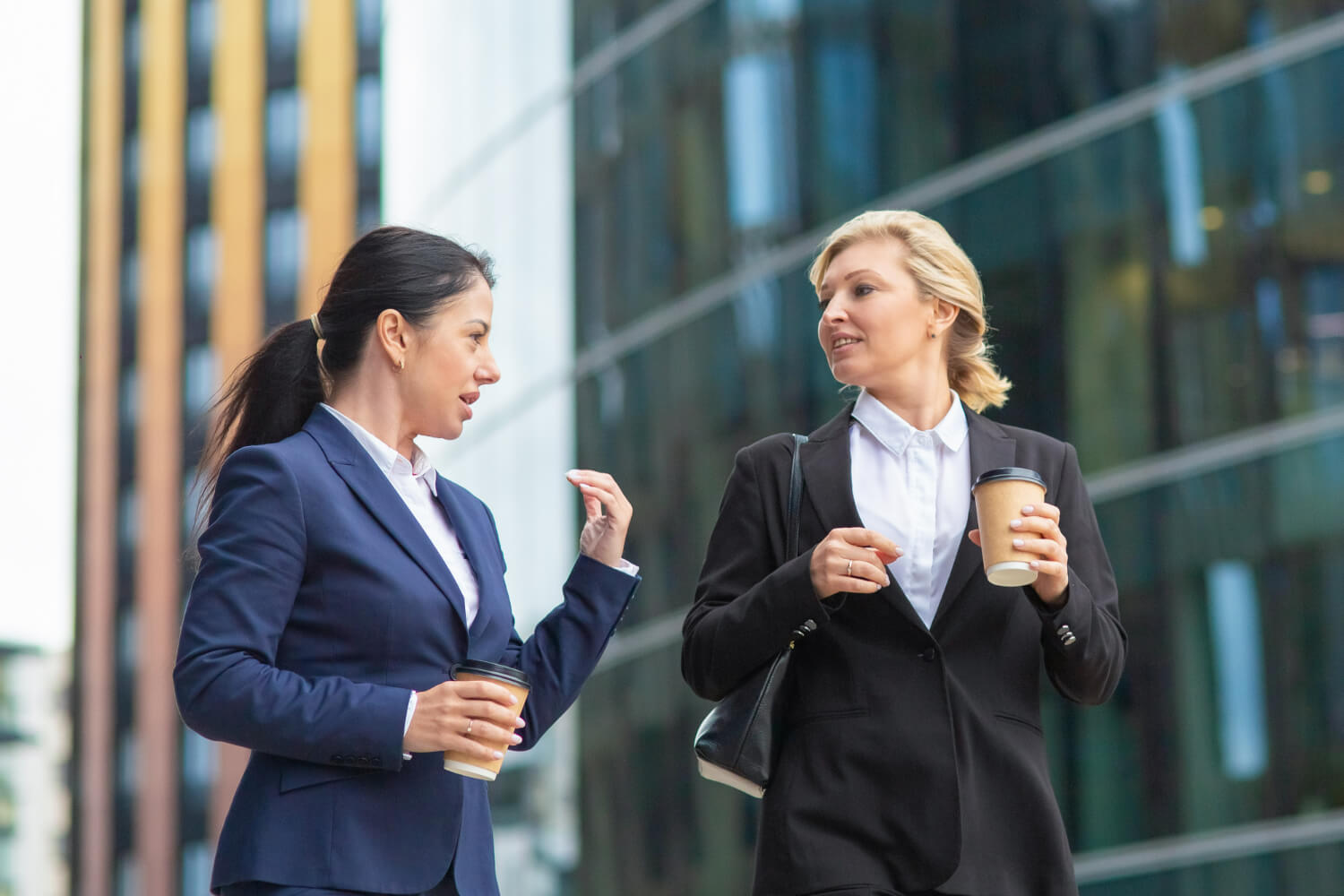 Female executives with takeaway coffee mentoring one another